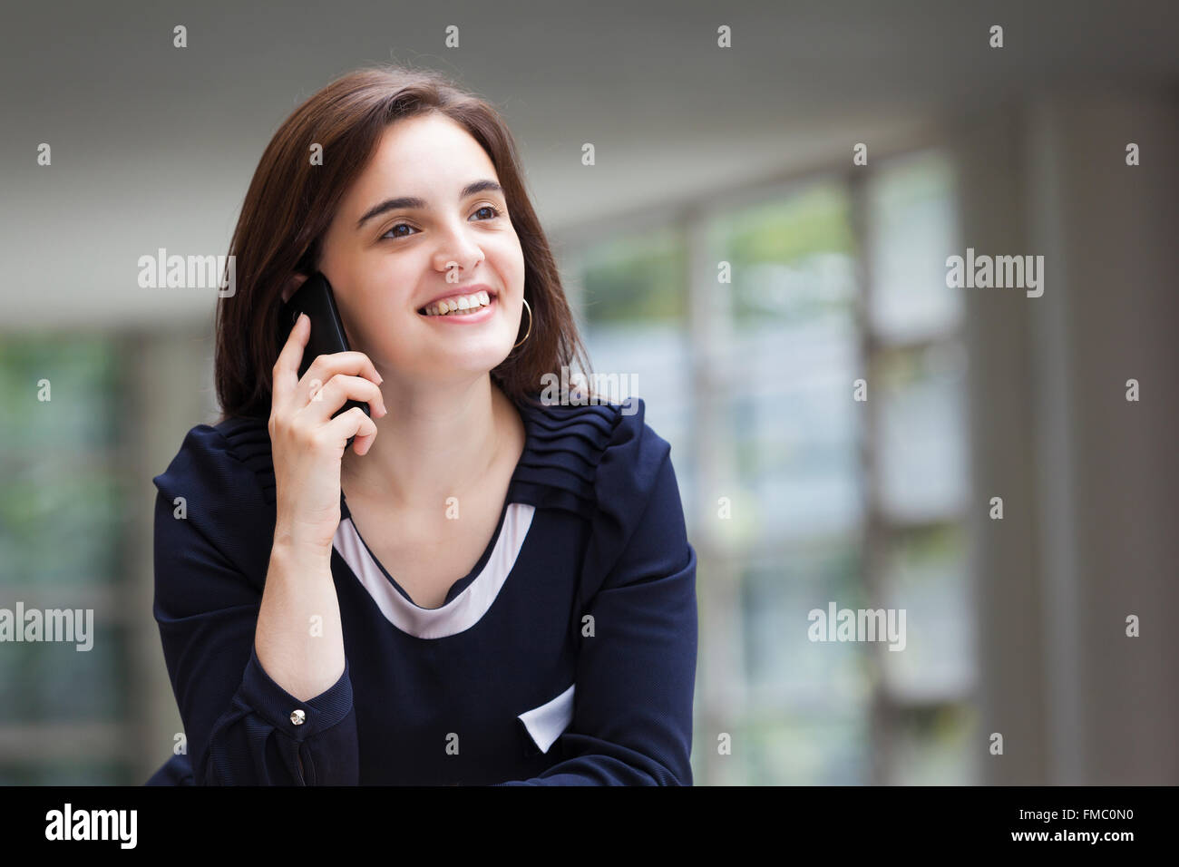 Lächelnde Geschäftsfrau auf modernes Bürogebäude am Handy sprechen Stockfoto