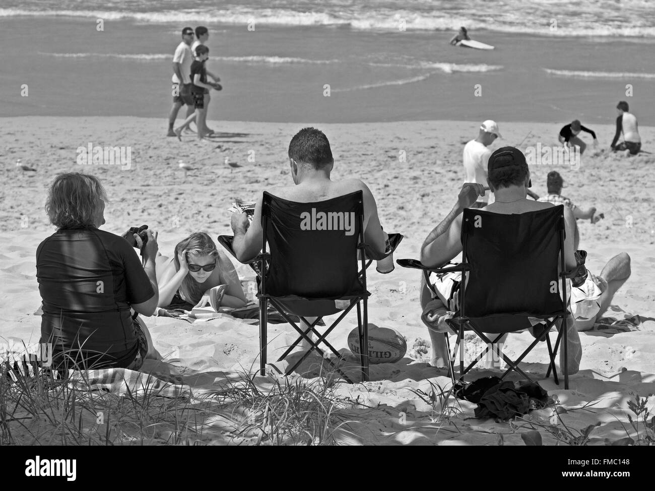 Strandbesucher, Sonnenbaden und im Sessel zurücklehnen, lesen, relaxen an der Gold Coast, Queensland Australien Stockfoto