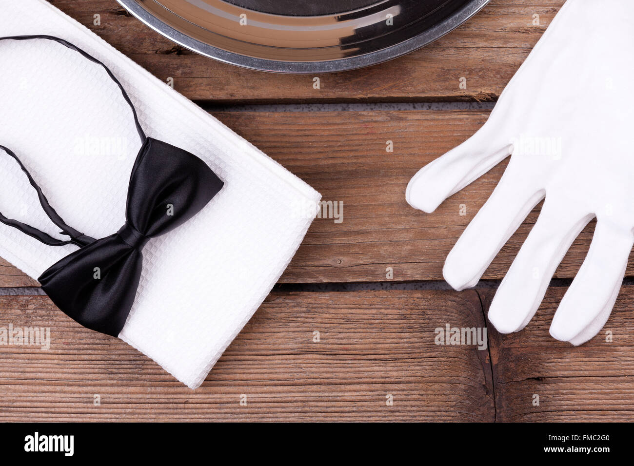Draufsicht von einem Kellner Tablett, Fliege, Handschuhe und eine Serviette auf hölzernen Hintergrund Stockfoto