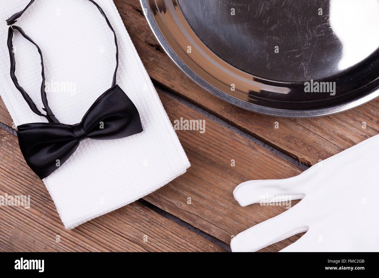 Draufsicht von einem Kellner Tablett, Fliege, Handschuhe und eine Serviette auf hölzernen Hintergrund Stockfoto