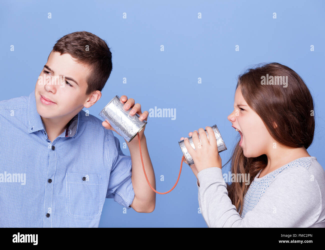 Kinder spielen mit einer Dose als ein Telefon auf blauem Hintergrund Stockfoto