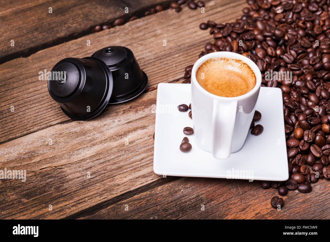 Tasse Kaffee und Hülsen auf Holztisch Stockfoto