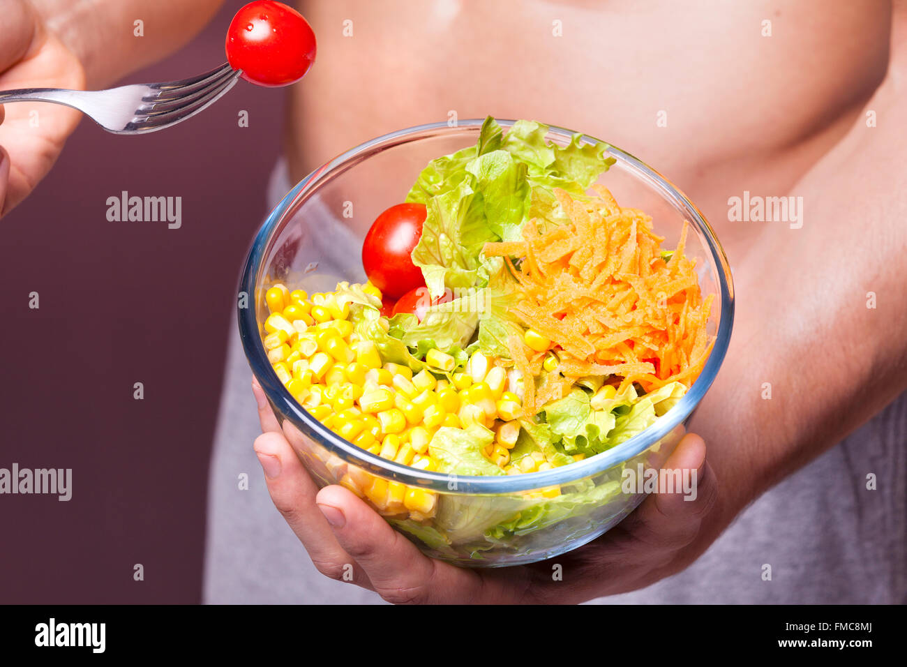 Nahaufnahme von einem Fit Mann hält eine Schüssel mit Salat auf Grunge Hintergrund Stockfoto