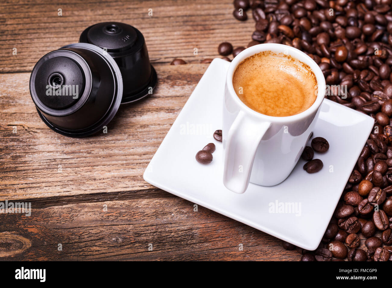 Tasse Kaffee und Hülsen auf Holztisch Stockfoto