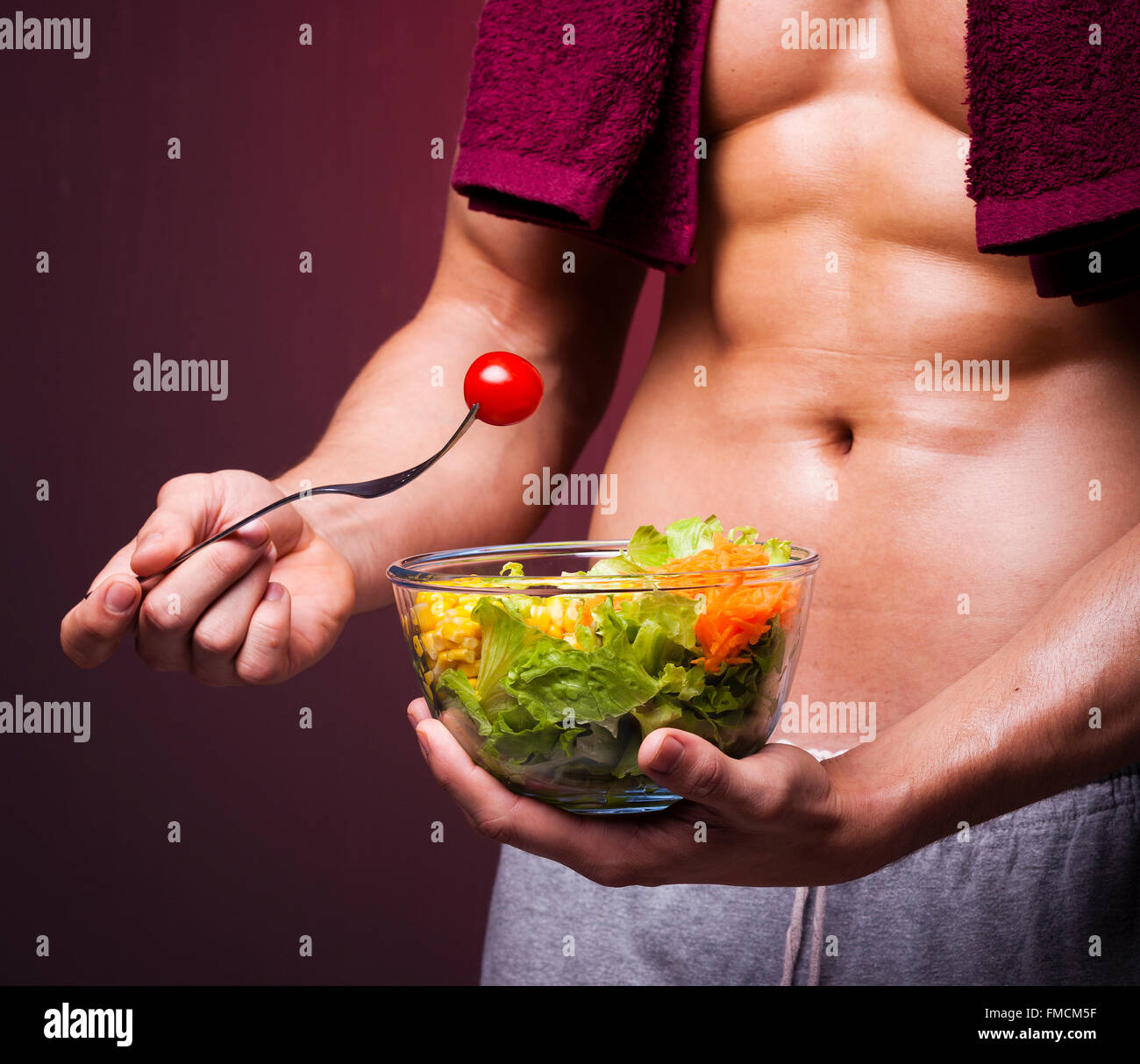 Muskulöser Mann hält eine Schüssel mit Salat auf Grunge Hintergrund Stockfoto