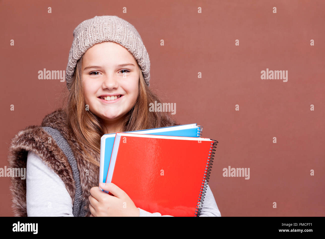 Teen Studentin Carring Notebooks vor braunem Hintergrund Stockfoto