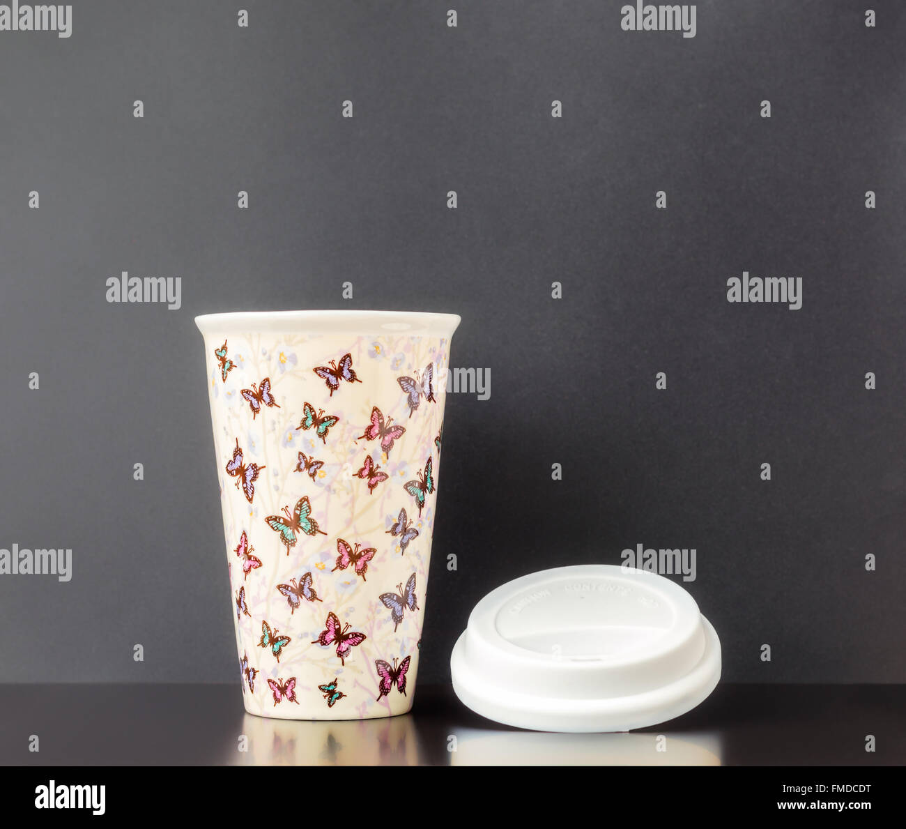 Deckel aus Keramik isolierte Tasse mit bunten Schmetterling Muster und dunkelgrauen Hintergrund. Stockfoto