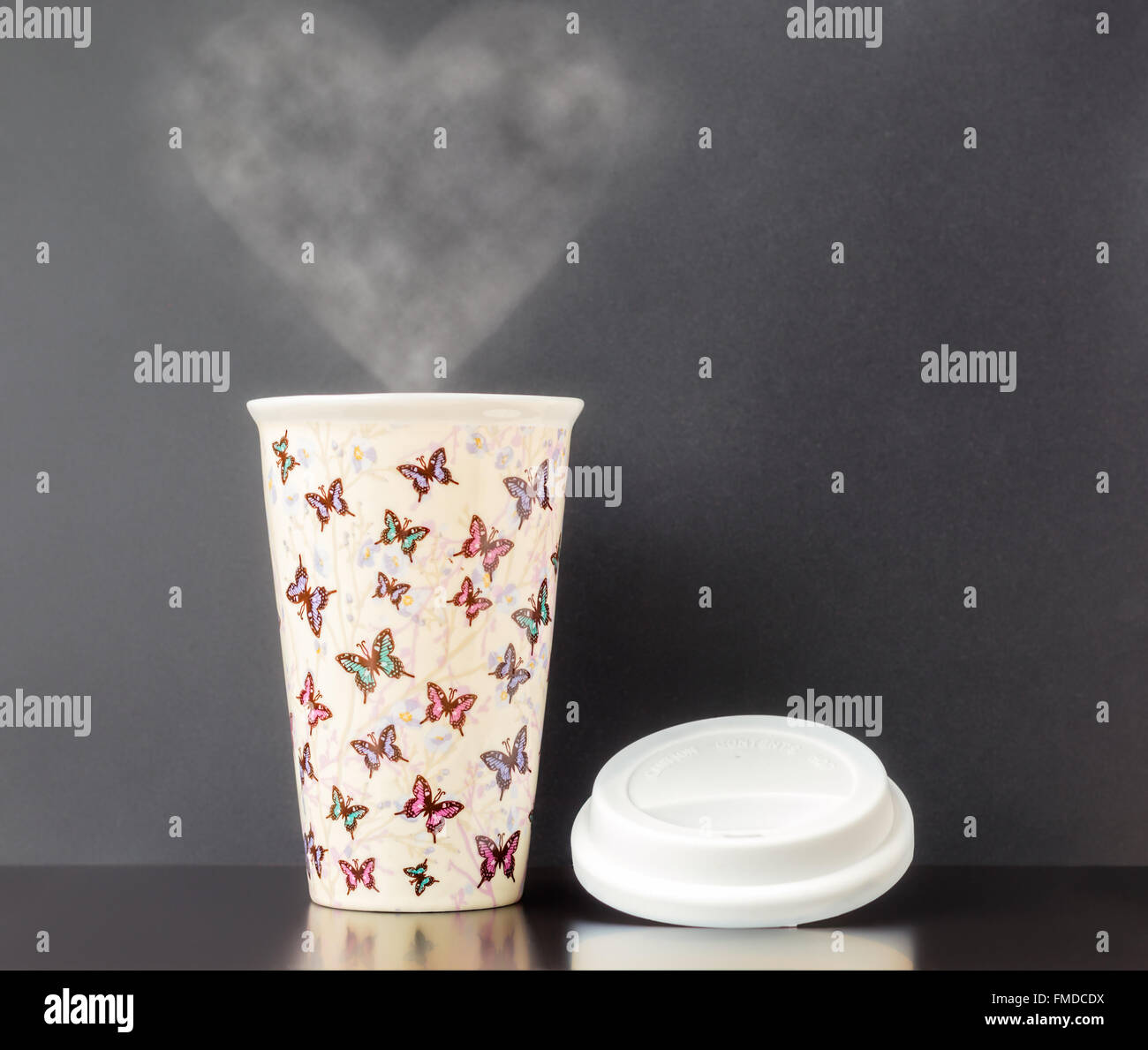 Keramik isoliert Tasse mit bunten Schmetterling Muster mit dunkelgrauen Hintergrund und Herz Form Dampf. Stockfoto