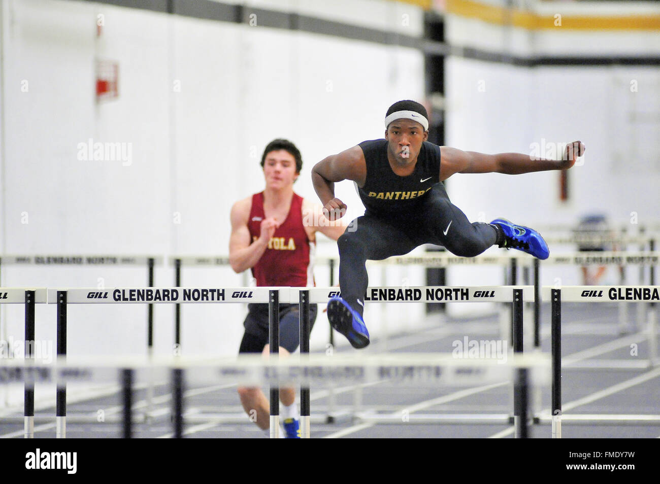Ein High-flying Runner auf dem Weg zum Sieg in der Hitze des 55 Meter Hürden bei einem indoor High School treffen. USA. Stockfoto