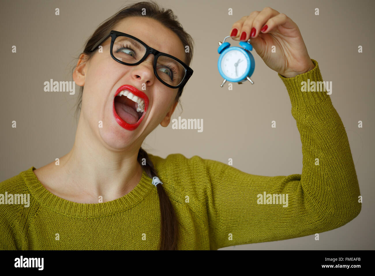 Kleine blaue Wecker in den Händen einer emotionalen jungen Frau Konzept der Zeitersparnis Stockfoto