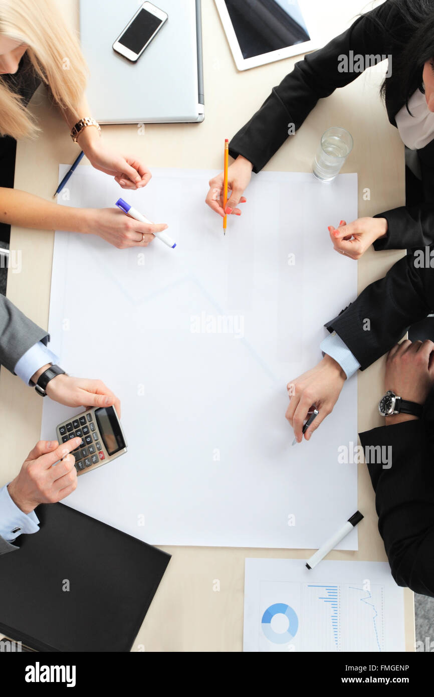 Geschäftsleute, die mit elektronischen Geräten treffen am Tisch sitzen Stockfoto