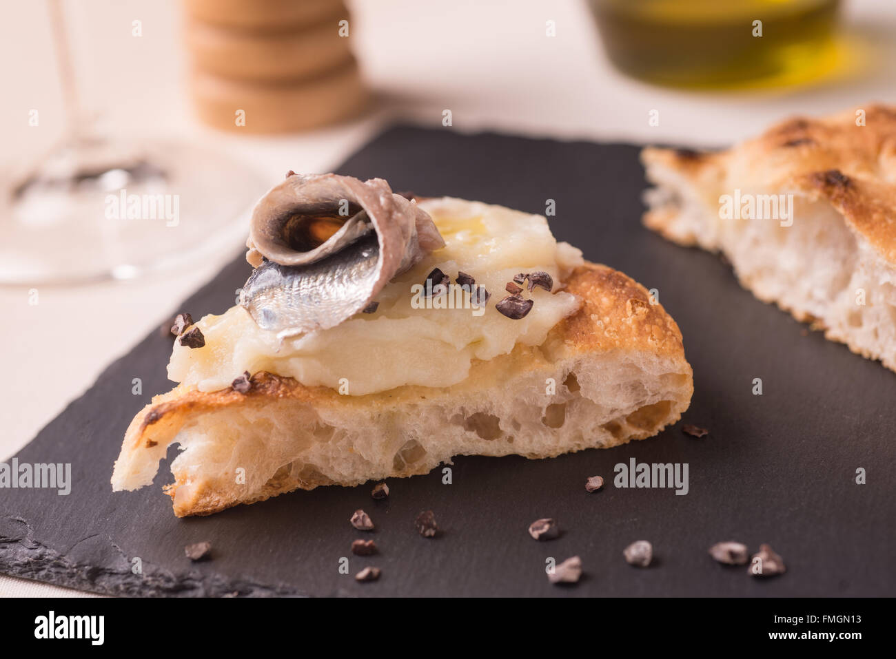 Scheibe der Pizza Gourmet mit Kartoffeln Sahne, marinierte Sardellen und geriebenem Rohkakao Stockfoto
