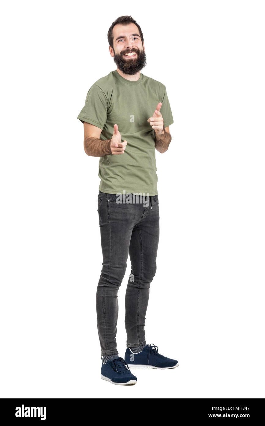 Spontan lachen, bärtiger Mann in grün T-shirt zeigenden Fingern in die Kamera. Ganzkörper-Länge-Porträt über weißen isoliert Stockfoto