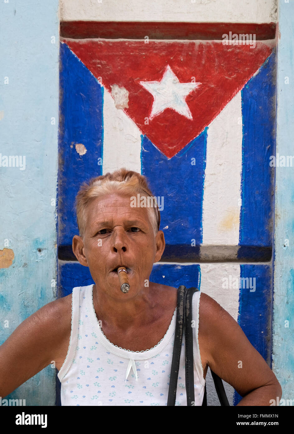 Kubanische Frau Rauchen Zigarre von verwitterten Mauer mit bemalten kubanische Flagge, Habana Vieja, Havanna, Kuba Stockfoto