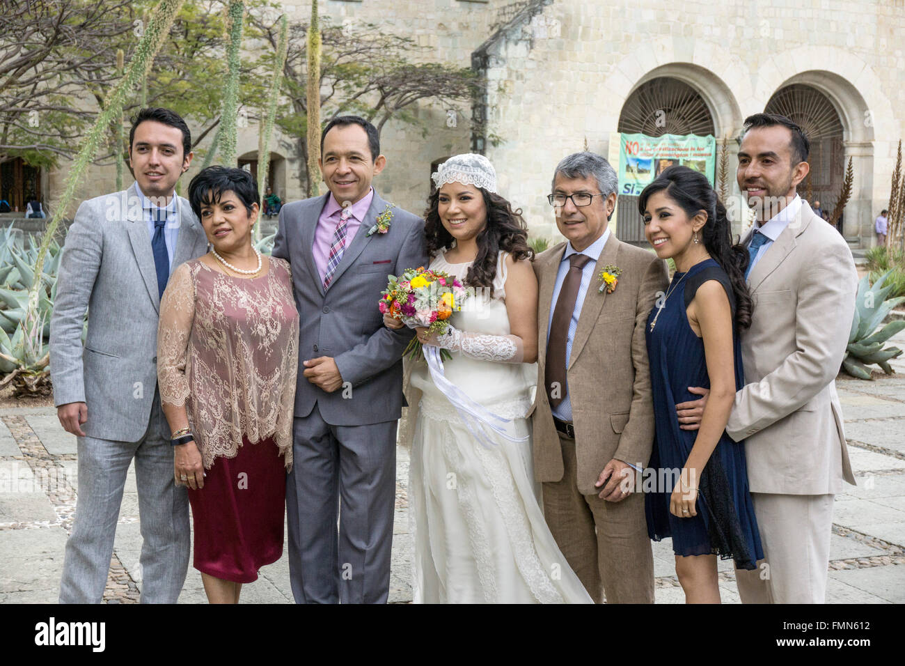 Mexikanische Hochzeitsgesellschaft posieren für Porträt auf der Kirche Santo Domingo Plaza mit lächelnden Braut hält kleine Strauß Frühlingsblumen Stockfoto