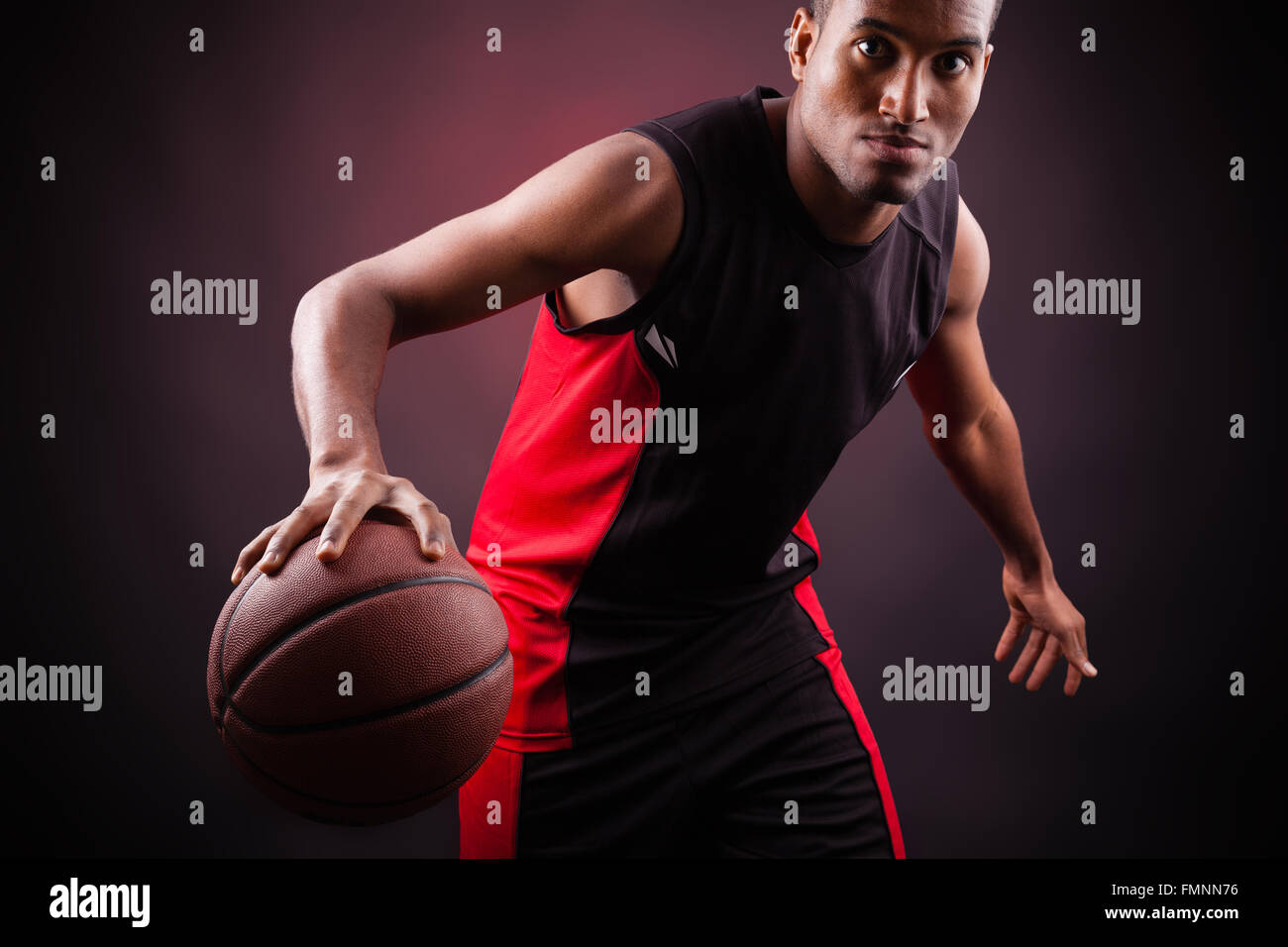 Porträt des jungen männlichen Basketballer vor schwarzem Hintergrund Stockfoto