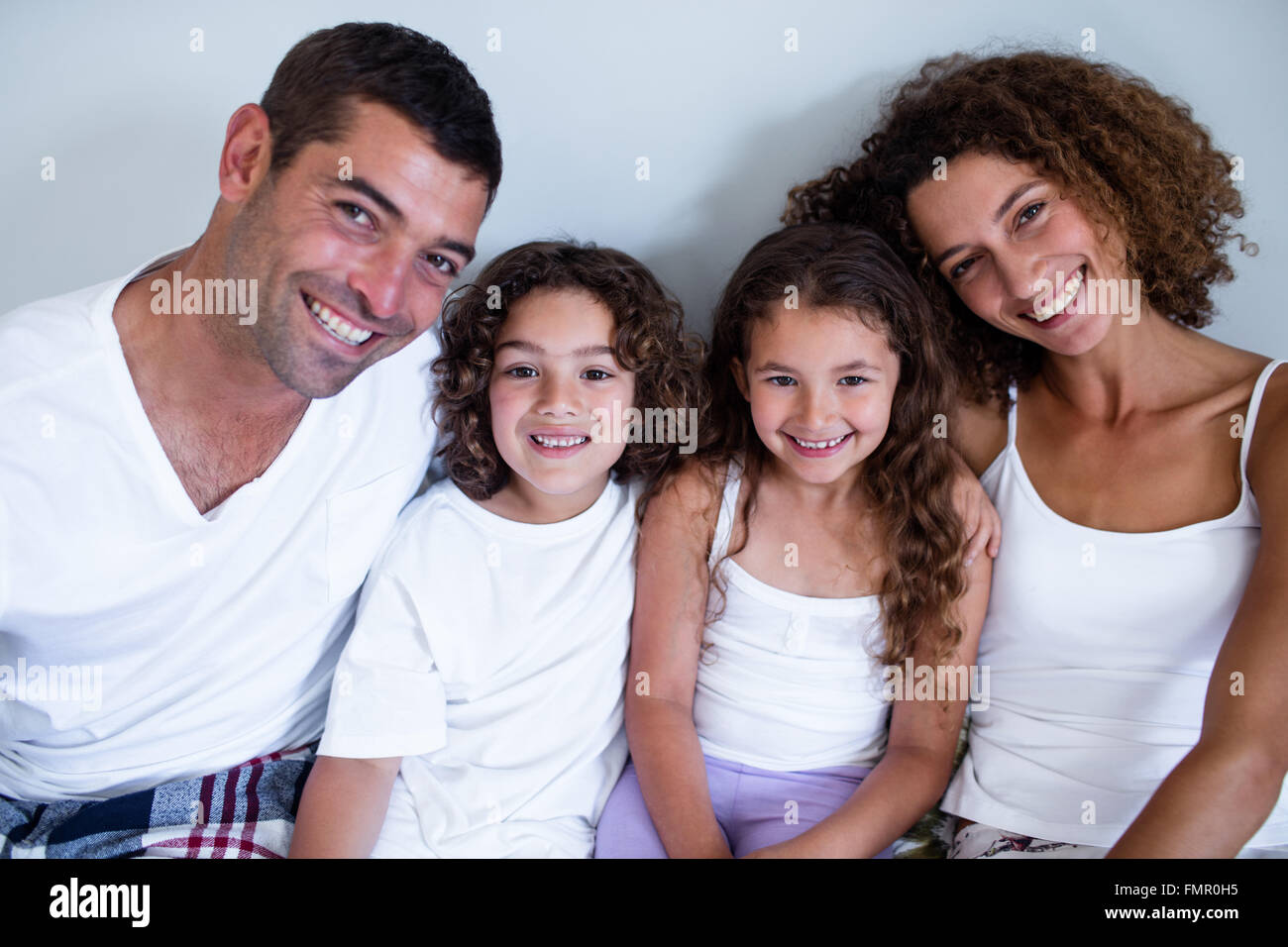 Porträt der Familie Zusammensitzen auf Bett Stockfoto