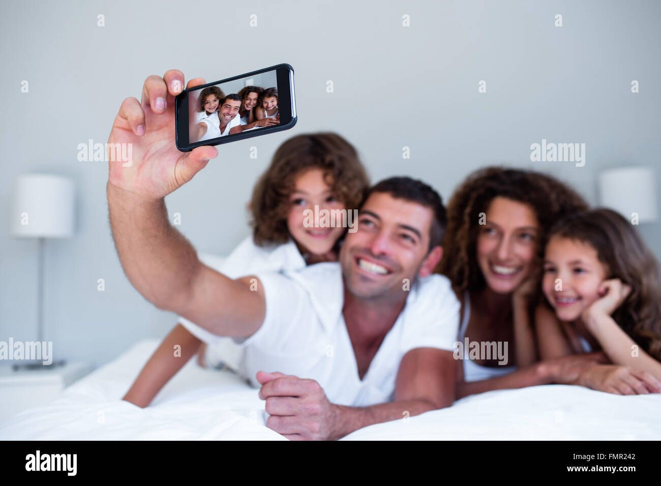 Glückliche Familie, die eine Selfie auf Bett Stockfoto