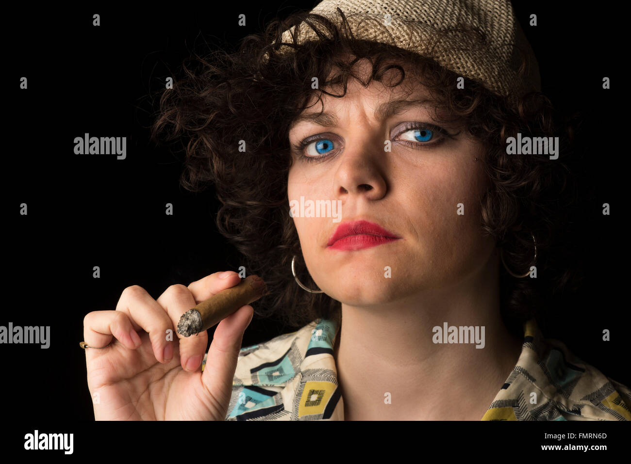 Hübsche junge kaukasischen Frau Rauchen Zigarre mit intensiven Blick auf Kamera und dunklem Hintergrund Stockfoto