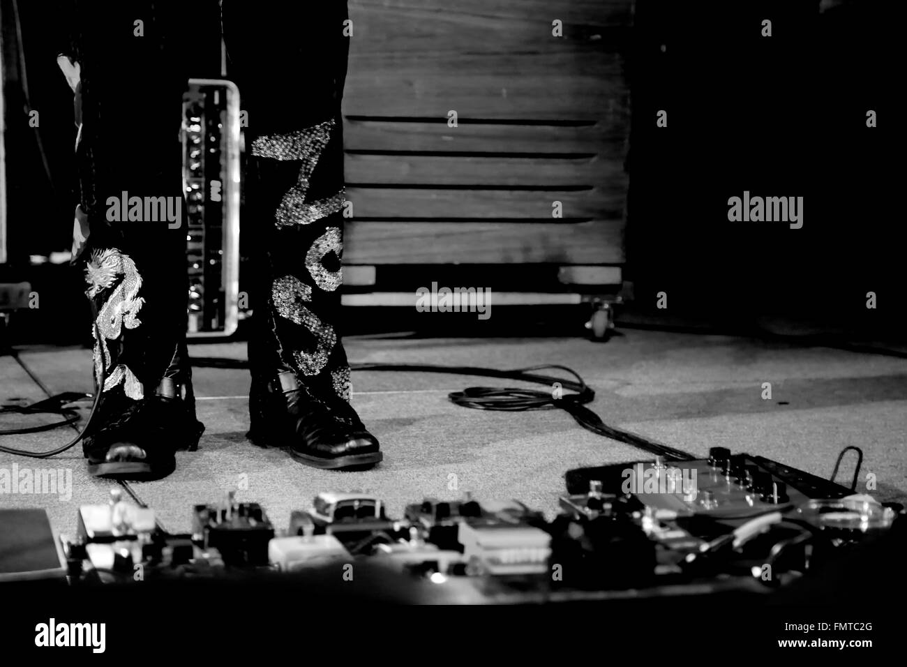 Gitarren-Pedale auf der Konzertbühne in schwarz und weiß mit Füßen Stockfoto