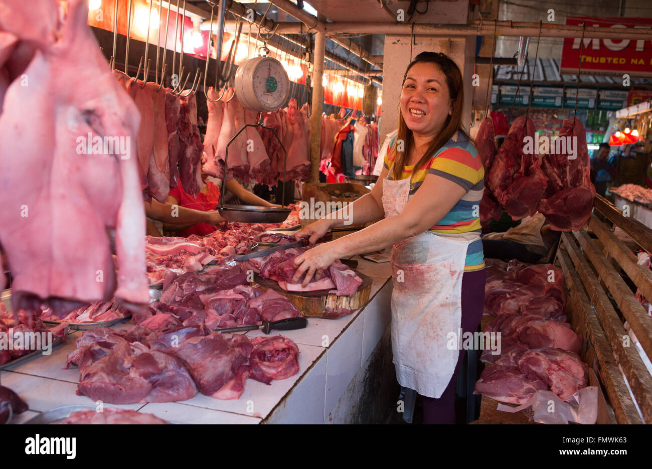 Ein philippinische Fleisch-Lieferanten bereitet Schweinefleisch Gelenke für Verkauf in den nassen Markt Talisay, Cebu City, Philippinen Stockfoto