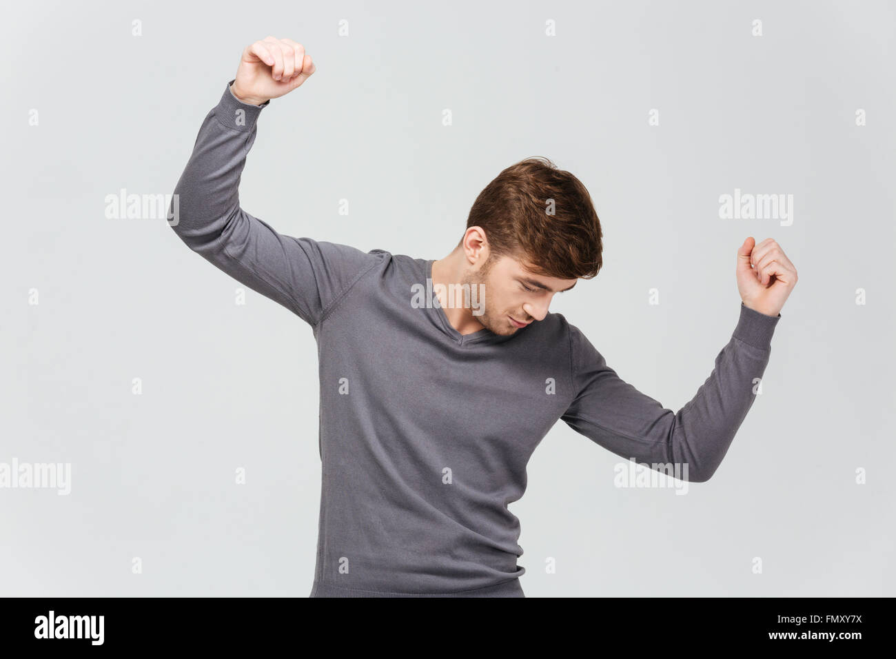 Attraktive junge Mann im grauen Pullover über weißem Hintergrund tanzen Stockfoto