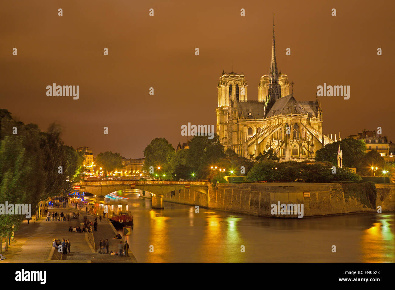 Paris - Notre-Dame Kathedrale in Nacht und viele junge Leute am Flussufer. Stockfoto