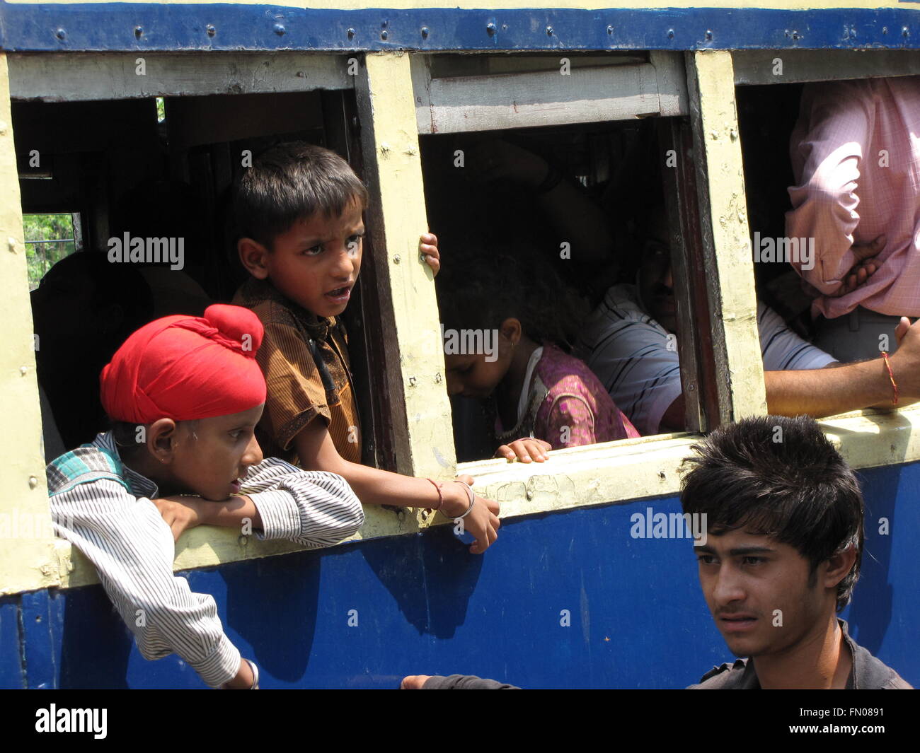 Indischer Junge mit roten Turban Reiten Kangra-Tal-Schnellzug in Indien sieht aus Fenster Stockfoto