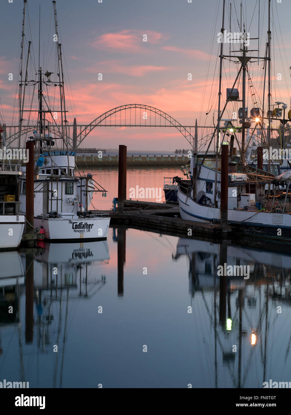 Yaquina Brücke am Newport Hafen mit Fischerbooten und Sonnenuntergang. Newport, Oregon Stockfoto