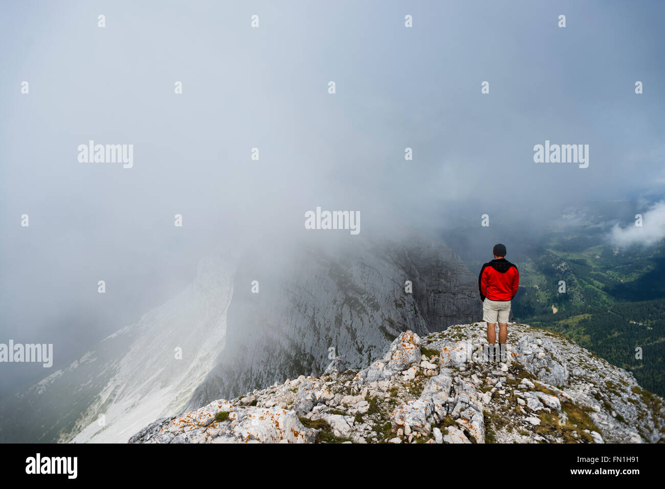Bergsteiger auf Wolken, Klippen und Panorama auf dem Gipfel des Mount Guffert im Rofangebirge, Tirol, Österreich Stockfoto