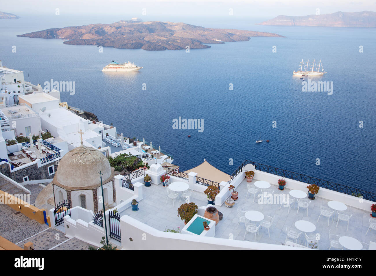 Santorini - die Aussichten von Fira nach Caldera mit der Nea Kameni Insel im Morgenlicht. Stockfoto