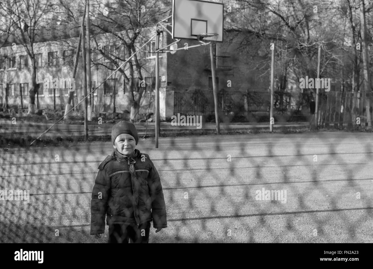 kleiner Junge spielt auf dem Sport-Spielplatz für Maschendrahtzaun Stockfoto