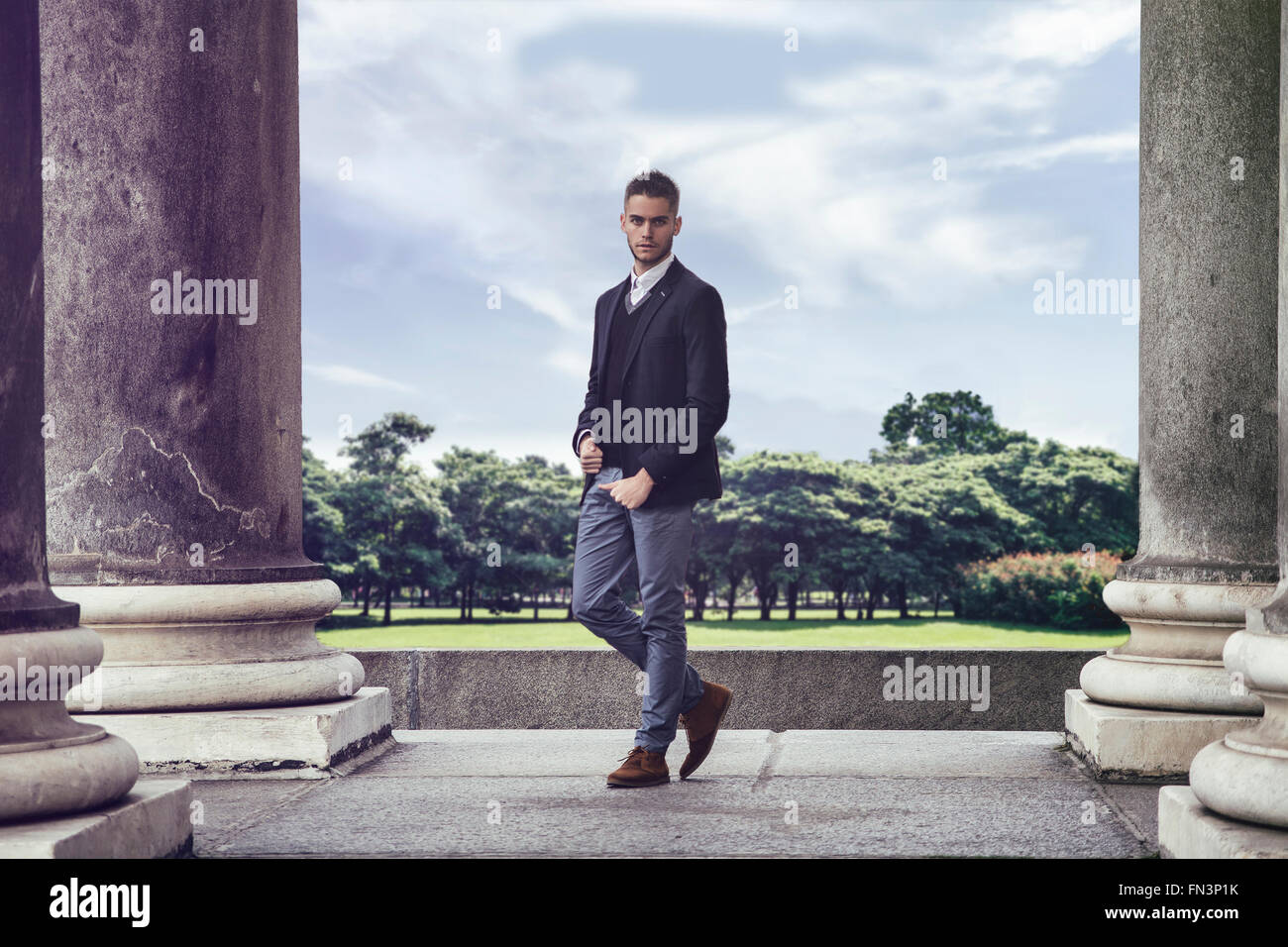 Porträt von stilvollen bärtiger Mann in eleganter Anzug, Blick in die Kamera gegen des Parks und historischen Gebäuden Stockfoto