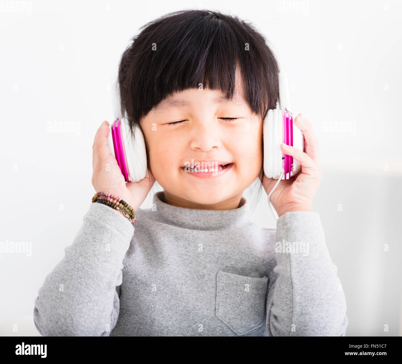 glückliche kleine Mädchen mit Kopfhörern hören Musik Stockfoto