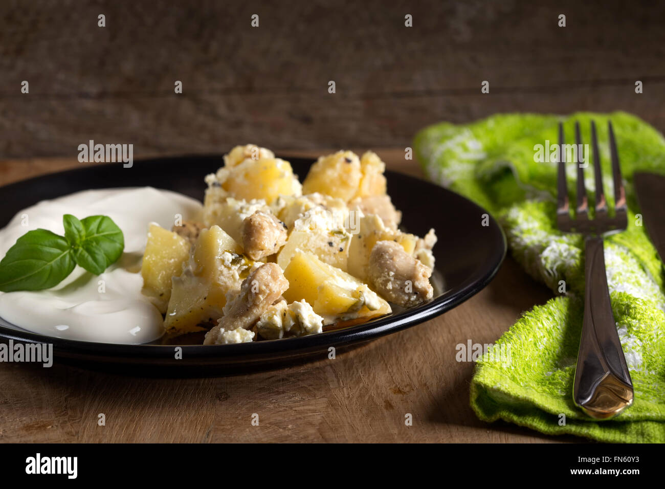 Kartoffelgratin mit Sauerrahm und Hühnerfleisch gebraten in Butter auf hölzernen Hintergrund Stockfoto