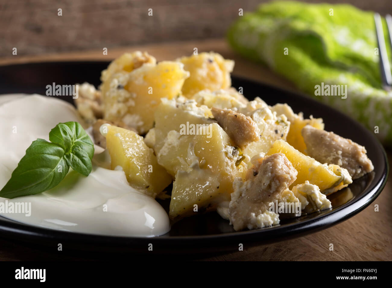 Kartoffelgratin mit Sauerrahm und Hühnerfleisch gebraten in Butter auf hölzernen Hintergrund Stockfoto