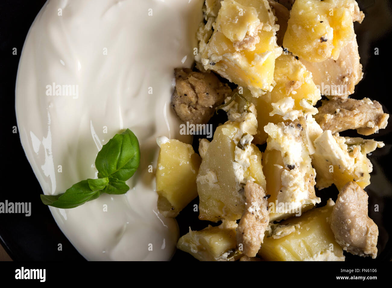 Kartoffelgratin mit Sauerrahm und Hühnerfleisch gebraten in Butter auf hölzernen Hintergrund Stockfoto