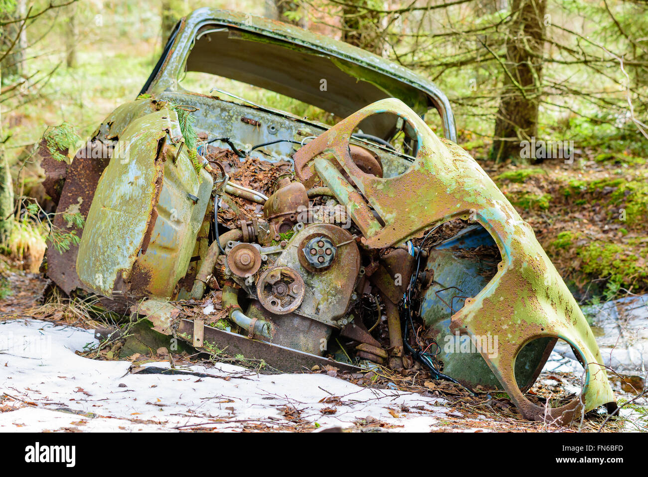 Eine alte und sehr degradiert Junk-Auto in der Natur hinterlassen. Schnee auf dem Boden. Stockfoto