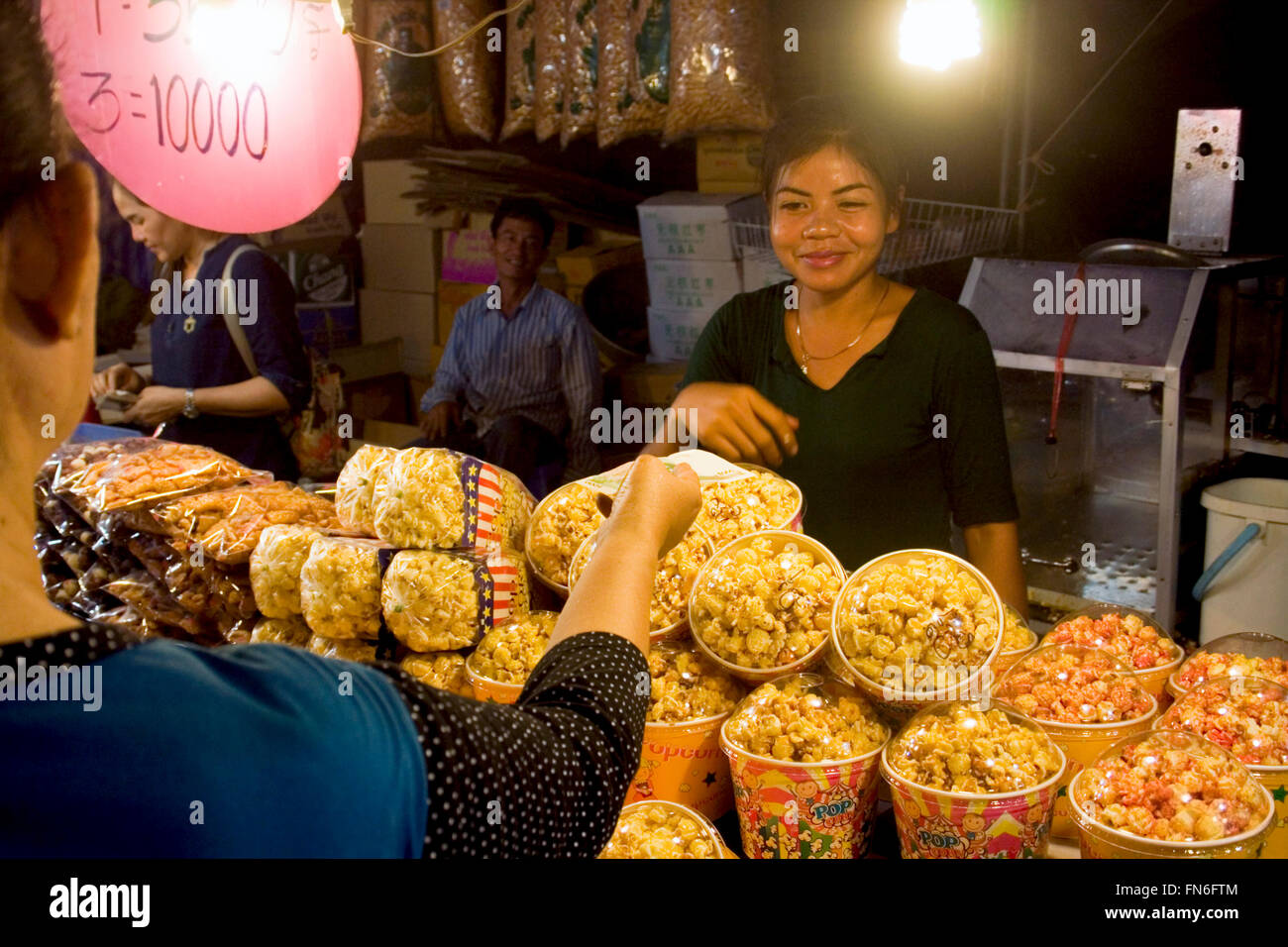 Eine Frau verkauft Popcorn aus Thailand an einen Kunden auf einer Straße Messe in Kampong Cham, Kambodscha. Stockfoto