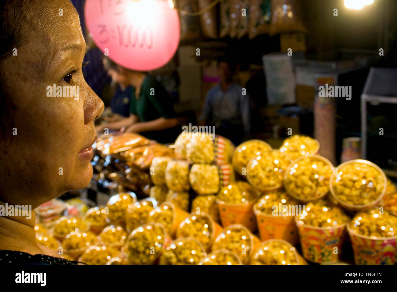 Eine Frau wartet auf eine Bestellung von Popcorn aus Thailand am Strassenfest in Kampong Cham, Kambodscha. Stockfoto
