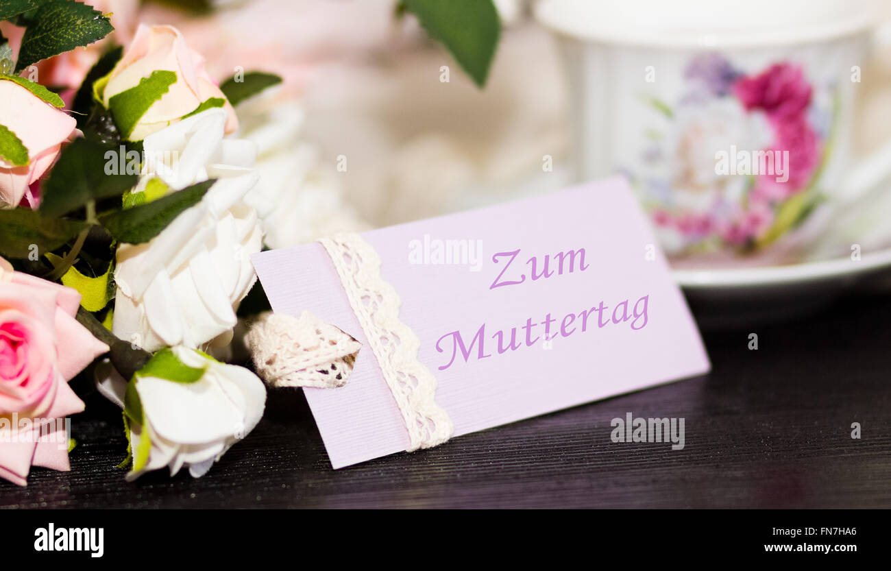 Mütter-Deutch Gratulation Tageskarte und Rosen auf Holzbrett Stockfoto