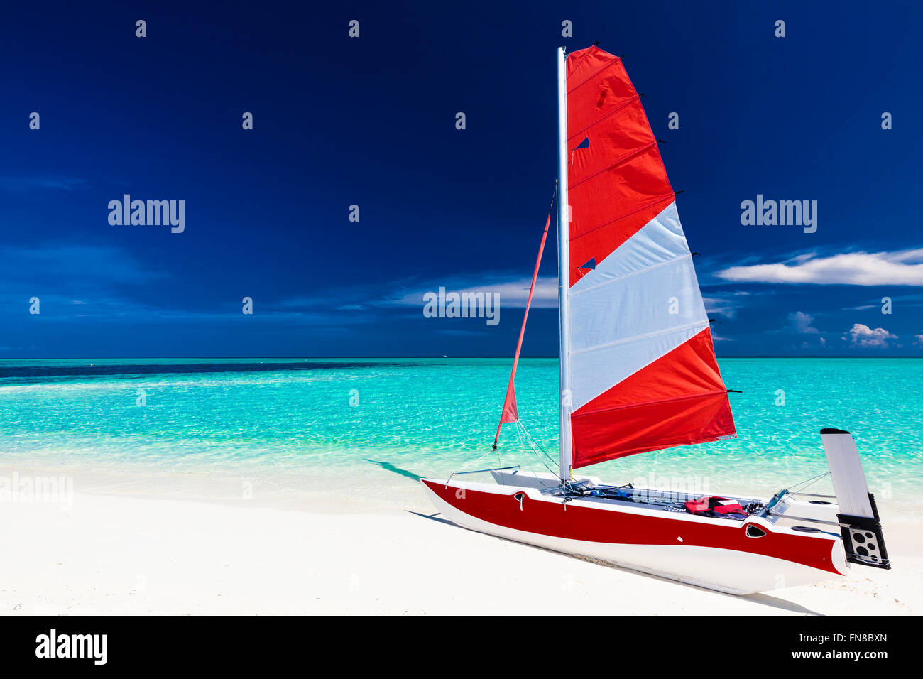 Segelboot mit roten Segel auf den Strand der einsamen tropischen Insel mit blauen Flachwasser Stockfoto