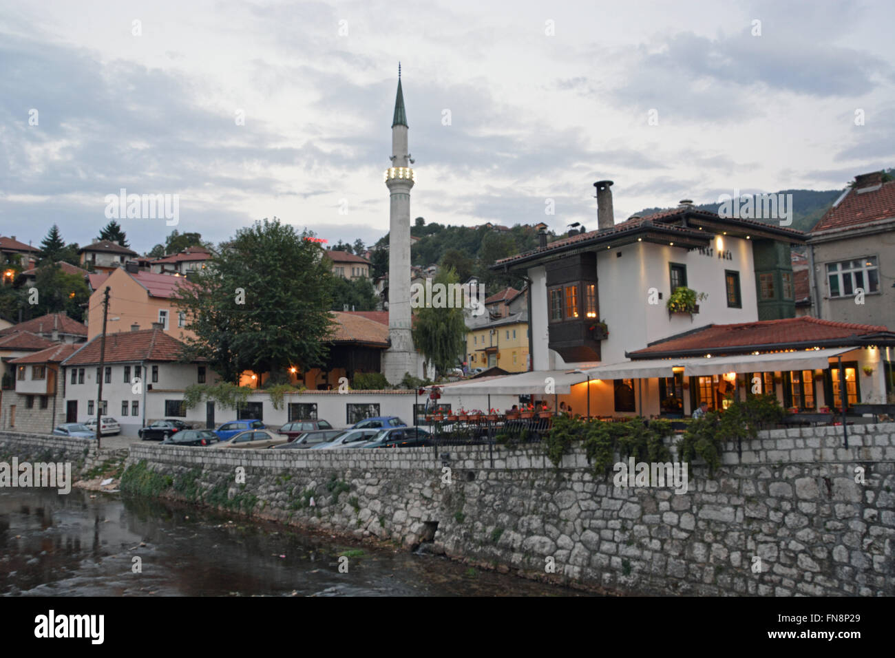 Eine Minarett erhebt sich über Gebäude über den Fluss aus der Nachbarschaft der Altstadt von Sarajevo, Bosnien-Herzegowina. Stockfoto