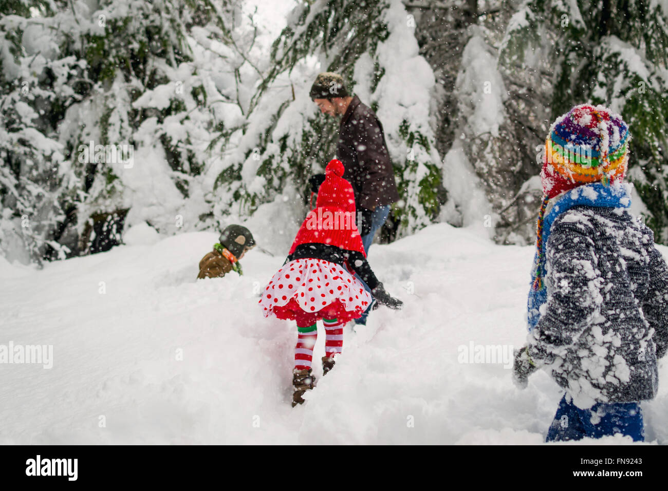 Vater, drei Kindern und einem Hund im Schnee spielen Stockfoto