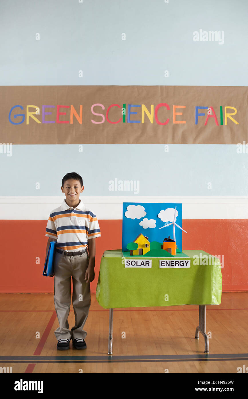 Ein Junge steht unter einem Green Science Fair Zeichen neben einer Solarstrom-Präsentation. Stockfoto