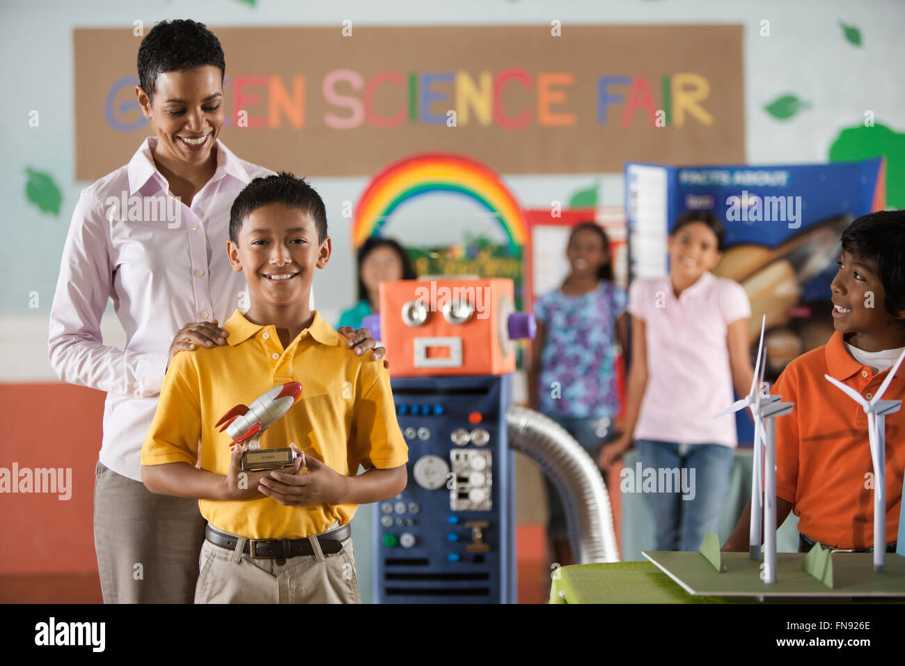 Ein Junge hielt eine Rakete Trophäe stehen vor der Klasse, mit einem Erwachsenen, eine Trophäe auf der Green Science Fair zu gewinnen. Stockfoto