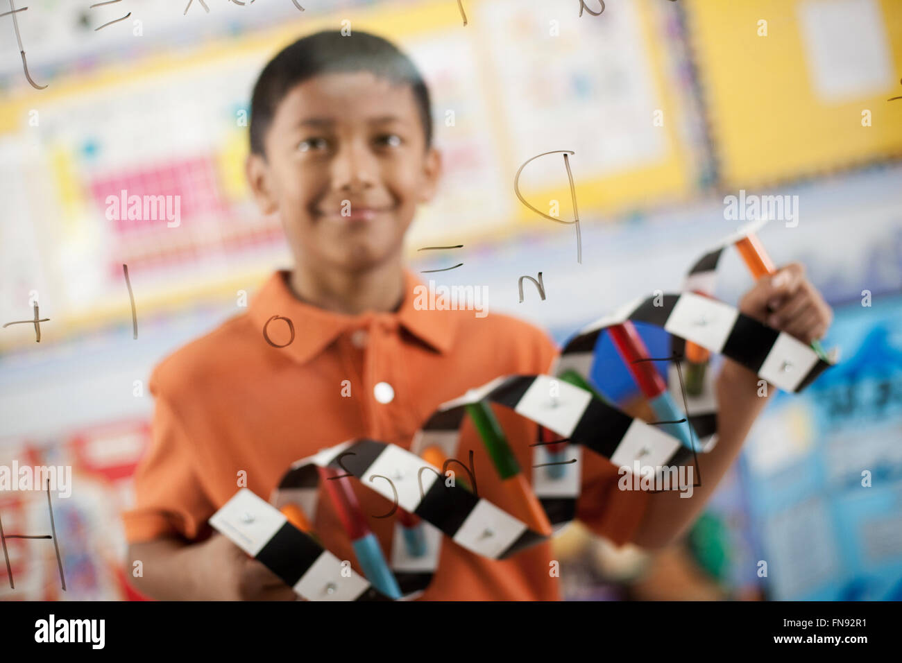 Ein Junge auf der Suche auf ein Brett mit schriftlichen wissenschaftlichen Formeln und Berechnungen, hält eine molekulare Struktur-Modell, ein double Stockfoto