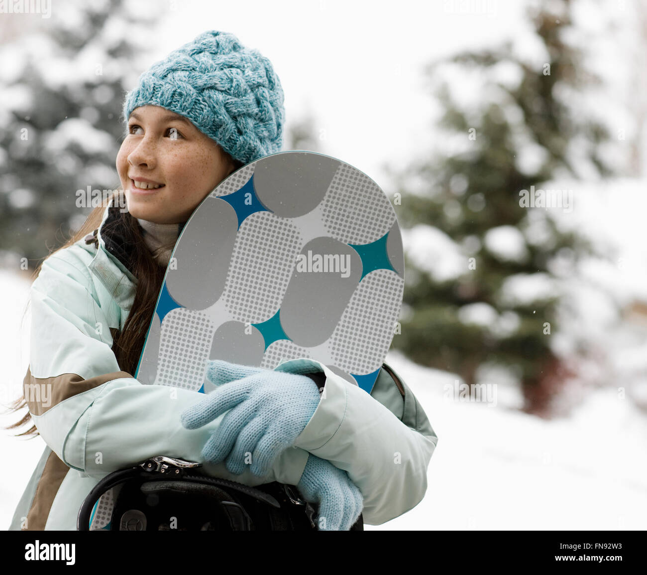 Winterschnee. Ein Mädchen in Hut und Handschuhe tragen ein Snowboard. Stockfoto