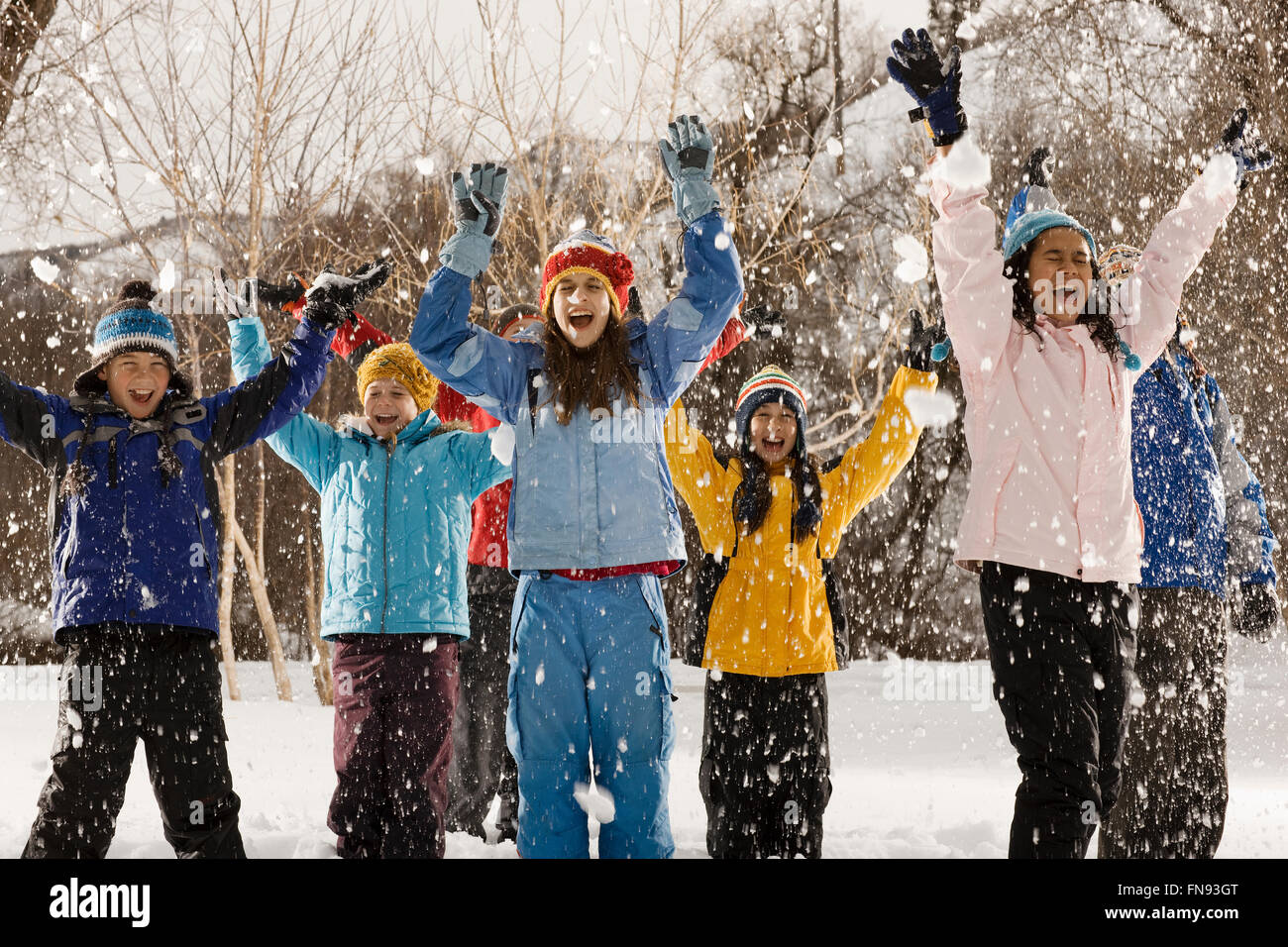 Eine Gruppe von Jugendlichen, jungen und Mädchen im Freien, Arme nach oben lachen unter fallenden Schnee Stockfoto