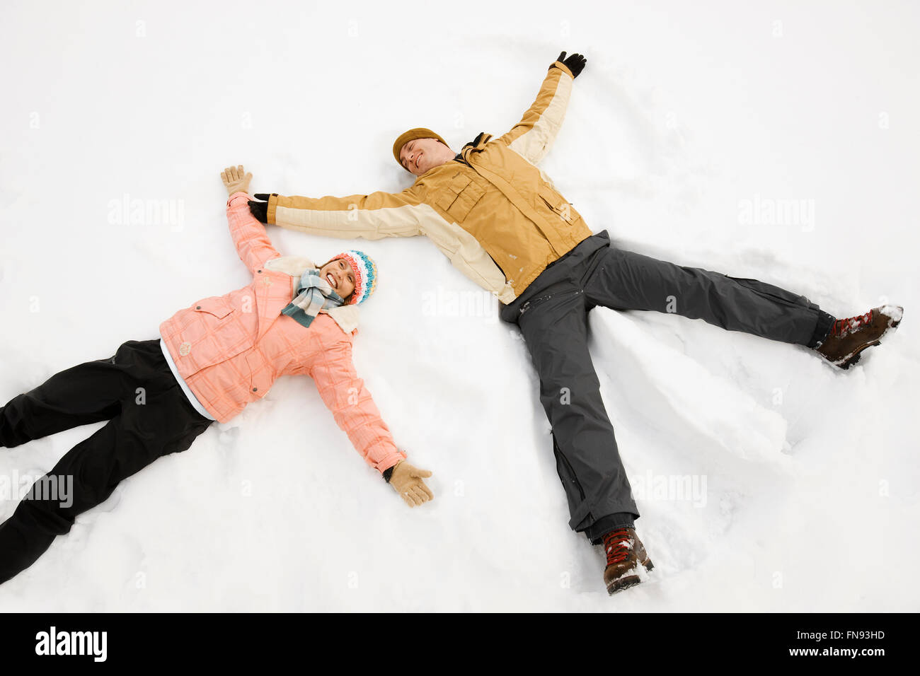 Zwei Menschen, Mann und Frau im Schnee liegen machen Schneeengel Formen. Stockfoto